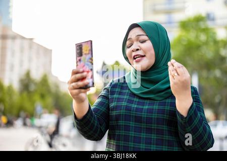 Muslimische Frau hat Videoanrufe per Handy in der Stadt Stockfoto