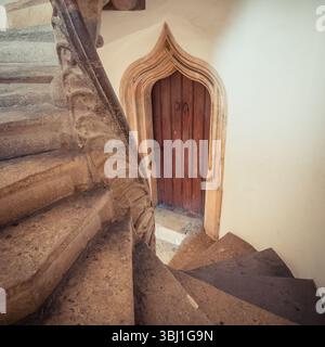 Alte Holztür und Wendeltreppe. Eine Wendeltreppe aus Stein in einem Turm. Stockfoto