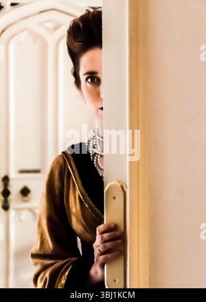 Eine Frau in einem Vintage-Kleid schaut hinter einer Tür heraus. Stockfoto