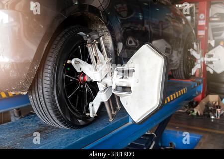 Die Radwuchtmaschine des Autos wird mit einem Laserreflektor kalibriert, der an jedem Reifen angebracht ist, um die mittlere Fahreinstellung einzustellen. Auto im Auto-Service. Auswuchtreifen Radmaschine. Stockfoto