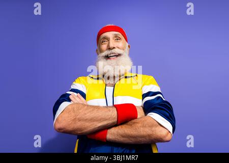 Glücklicher älterer Mann, der Retro-Activewear und Stirnband trägt, fröhlich und selbstbewusst aussieht und einen gesunden und aktiven Lebensstil führt Stockfoto