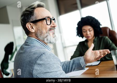 Verschiedene Geschäftsteams in einem formellen Meeting, in dem Projektstrategien in einer modernen Büroumgebung diskutiert werden Stockfoto