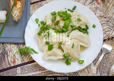 Hausgemachte Teigtaschen mit Kartoffelfüllung und frischen Kräutern. Stockfoto