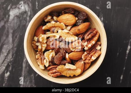 Verschiedene Nüsse in rustikaler Schüssel. Walnüsse Cashews Pekannüsse und Rosinen. Gesunder Bio-Snack. Gemischte trockene Früchte und Nüsse. Proteinreiche vegetarische Nahrung. Stockfoto