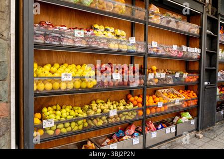 Taormina, Sizilien - Italien - 05-04-2025: Obst in Plastiktabletts vor einem Geschäft mit Äpfeln, Birnen, Orangen, Zitronen und Snacks, ordentlich angeordnet. Lo Stockfoto