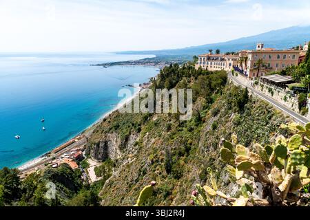 Taormina, Sizilien - Italien - 05-04-2025: Panoramablick auf die Küste von Taorminas mit klarem, blauem Meer, Vegetation am Hügel, Gebäuden an den Klippen und Dista Stockfoto