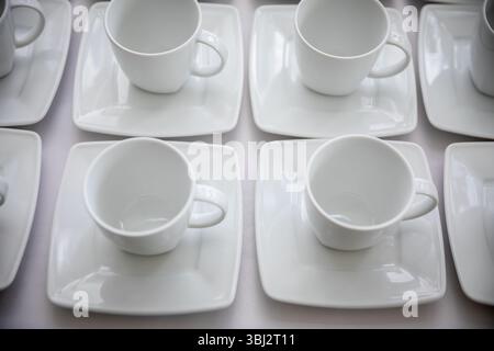 Schicke und elegante weiße Kaffeetassen auf modernen quadratischen Tellern für modernes Essen Stockfoto