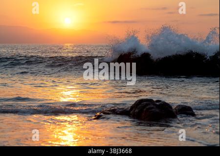 Eine Nahaufnahme des Sonnenuntergangs mit Einem bunten Sonnenuntergang-Himmel-Horizont Einer Welle, die an Land stürzt Stockfoto