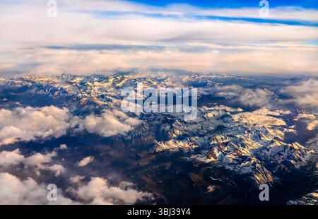 Aus der Vogelperspektive auf die schneebedeckten Berge der Sierra Nevada in Kalifornien bei Sonnenuntergang, die dramatische Gipfel und zerklüftetes Gelände mit goldenem Licht zur Geltung bringen Stockfoto