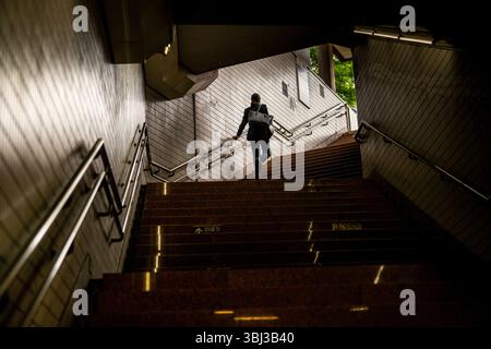 Eine Geschäftsfrau, die im dramatischen Licht in Tokio, Japan, U-Bahn-Treppen hinaufklettert Stockfoto