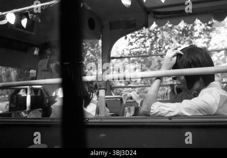 Chinesischer Busfahrer aus den späten 2000er Jahren, Hand auf Kopf, Schwarz-weiß-Straßenfoto Stockfoto