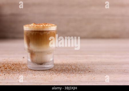 Cappuccino oder Latte mit Milchschaum und Karamell in einem Glas auf hellbraunem Marmorhintergrund. Vorderansicht mit Kopierbereich. Stockfoto