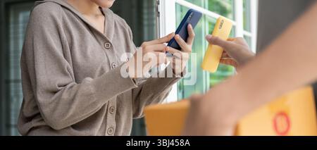 Smile Asiatische Frau scannt QR-Code für die Bezahlung von Lebensmitteln. Liefermann schickt Lieferexpress. Online-Shop, Papierbehälter, zum Mitnehmen, Postbote, Lieferservice, Stockfoto