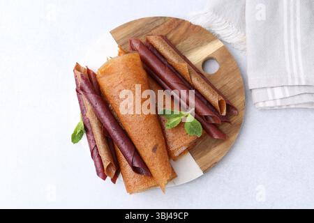 Köstliche Fruchtlederrollen und Minzbonbons auf dem hellen Tisch, Blick von oben Stockfoto