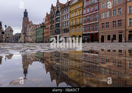 Breslau, Polen - 29. Januar 2025: Die berühmten antiken Gebäude spiegeln sich in einer Pfütze auf dem mittelalterlichen Marktplatz in der Breslau Altstadt in Polen wider. Stockfoto