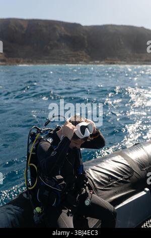 Taucher, der die Ausrüstung vorbereitet, sitzt auf einem Schlauchboot, bevor er ins Meer taucht Stockfoto