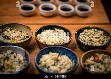Gourmet Couscous Tasting Setup mit kleinen Saucen auf Holztisch Stockfoto