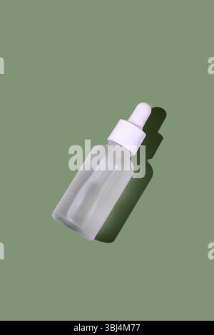 Weiße transparente Kosmetikflasche mit Pipette, grüner Hintergrund Stockfoto