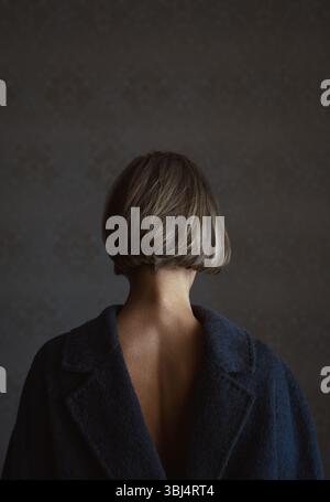 Rückansicht einer blonden Frau im Mantel umgekehrt Stockfoto