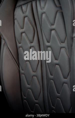 Vordersitz aus Leder in einem Auto. Moderne, schwarze Ledersitze im SUV-Interieur mit Bronzefarben. Stockfoto