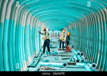 (250613) -- GUANLING, 13. Juni 2025 (Xinhua) -- Arbeiter bauen einen Sightseeing-Korridor auf der Baustelle der Huajiang Grand Canyon Brücke in der südwestlichen chinesischen Provinz Guizhou, 11. Juni 2025. Touristische Ausrüstung an der Huajiang Grand Canyon Bridge wird derzeit gebaut. Die Hängebrücke hat eine senkrechte Höhe von 625 Metern vom Brückendeck bis hinunter zur Flussoberfläche – etwa doppelt so hoch wie der Eiffelturm. Die 2.890 Meter lange Brücke mit einer Spannweite von 1.420 Metern ist auch die weltweit größte Spannbrücke, die in einem bergigen Gebiet gebaut wurde. Es wird erwartet, dass es für Traffi geöffnet wird Stockfoto