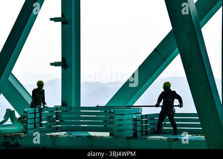(250613) -- GUANLING, 13. Juni 2025 (Xinhua) -- Arbeiter bauen einen Sightseeing-Korridor auf der Baustelle der Huajiang Grand Canyon Brücke in der südwestlichen chinesischen Provinz Guizhou, 11. Juni 2025. Touristische Ausrüstung an der Huajiang Grand Canyon Bridge wird derzeit gebaut. Die Hängebrücke hat eine senkrechte Höhe von 625 Metern vom Brückendeck bis hinunter zur Flussoberfläche – etwa doppelt so hoch wie der Eiffelturm. Die 2.890 Meter lange Brücke mit einer Spannweite von 1.420 Metern ist auch die weltweit größte Spannbrücke, die in einem bergigen Gebiet gebaut wurde. Es wird erwartet, dass es für Traffi geöffnet wird Stockfoto