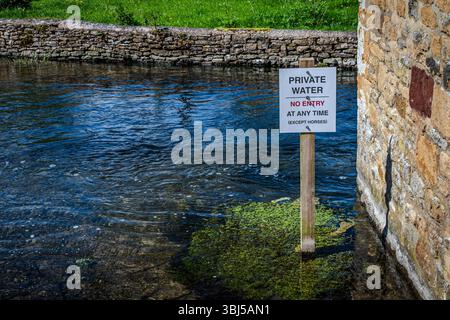 Wo sich das River Eye zu einem flachen Bach verengt, steht ein Schild für eine alte Regel: „Private Water — No Entry (außer Pferden) Stockfoto