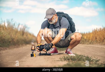Ein Fotograf hockte sich und hielt die Kamera mitten auf der Feldstraße. Fotos von türkischer Kaffeemaschine. Konzept der Reise- und Outdoor-Adv Stockfoto