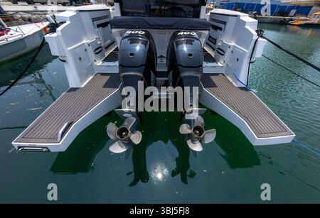 Nahaufnahme der zwei Außenbordmotoren eines Luxusbootes, die am Yachthafen angedockt sind. Sauberes, modernes Design mit Reflexen auf Wasser und sonnigem Wetter. Stockfoto