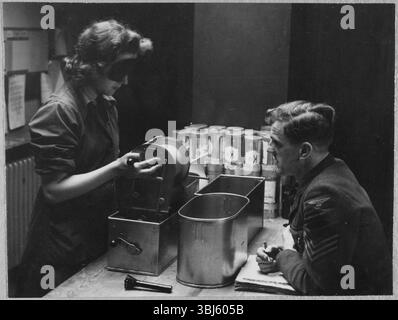 Royal Air Force No. 2 School of Photography, Palatine Road, Blackpool, Lancashire, 1942-1943. Eine Auszubildende der Women's Auxiliary Air Force (WAAF), die während der Prüfung auf dem Trade Test Board am Ende des Schulungskurses mit einer Augenmaske eine Rolle fotografischen Films bearbeitet, während sie eine Augenmaske trägt, um die Arbeit im Dunkeln zu simulieren. Die RAF’s No. 2 School of Photography wurde im August 1940 gegründet, um den schnell wachsenden Bedarf an Fotografen und Fototechnikern zu decken, die während des Zweiten Weltkriegs bei der Luftaufklärung helfen sollten. Die Schule war am Blackpool Technical College und am Palatine Second untergebracht Stockfoto