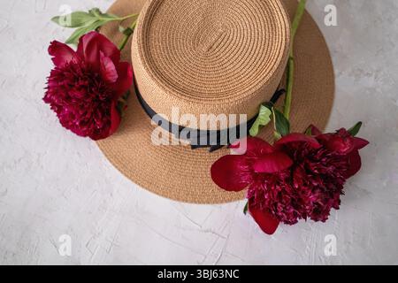 Strohhut mit Pfingstrosenblüten Stockfoto