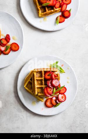 Waffelteller mit frischen Erdbeeren und Minzblättern auf hellem Hintergrund. Stockfoto