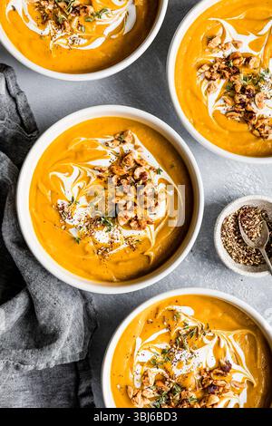 Schüsseln mit cremiger Kürbissuppe garniert mit Sahne, Nüssen und Kräutern. Stockfoto