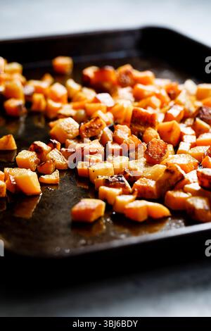 Nahaufnahme gerösteter Butternusskürbwürfel auf einem Backblech. Stockfoto