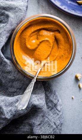 Eine Schüssel cremige Orangensauce mit einem Löffel auf einer strukturierten Stoffoberfläche. Stockfoto