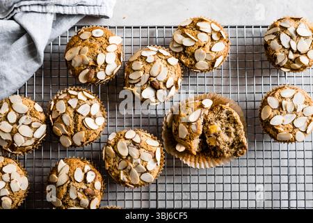 Muffins mit Mandelstopfen, die auf einem Gittergestell mit einer Stoffserviette in der Nähe abkühlen. Stockfoto