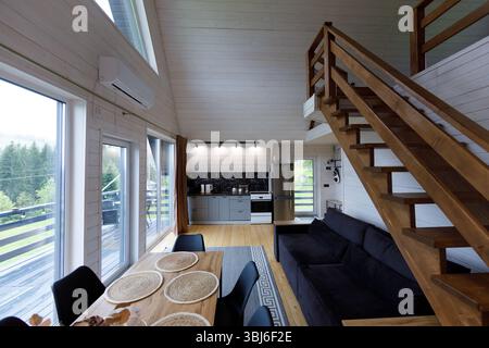 Helle und luftige Innenausstattung der Kabine mit Holzakzenten, einer gut ausgestatteten Küche, einem Essbereich mit elegantem Dekor und einer Treppe, die zu einem Oberteil führt Stockfoto