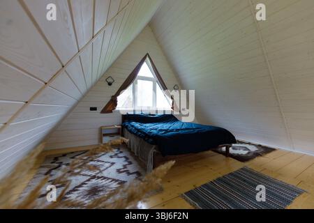 Dieses Bild zeigt ein bezauberndes Schlafzimmer mit A-Rahmen, bequemem Bett, stilvoller Einrichtung, großen Fenstern für natürliches Licht und einem Stockfoto