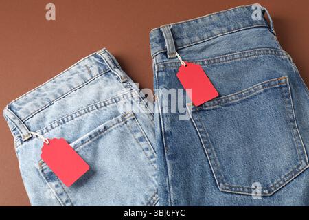 Jeans mit Tags auf braunem Hintergrund, Draufsicht Stockfoto