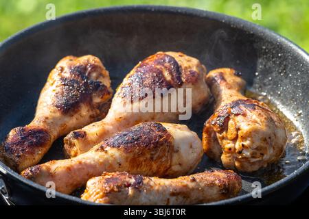 Hähnchenschenkel werden in einer Pfanne im Garten gebraten Stockfoto