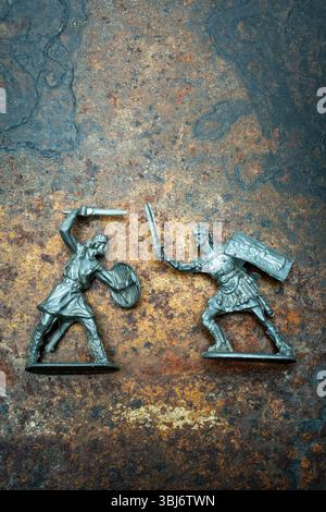 Zwei Miniaturfiguren aus Plast zeigen einen Krieger mit Schild und Schwert, der gegen einen römischen Soldaten gerichtet ist, der Schwert und Schild schwingt. Stockfoto