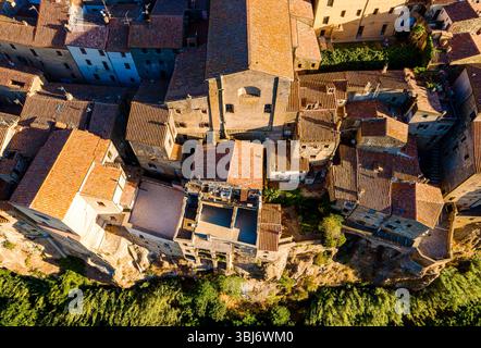 Aus der Vogelperspektive auf Pitigliano, Toskana, Italien, mit warmen orangen Dächern, goldenen Tönen und der charmanten Stadt auf einem Hügel in einer malerischen Weinregion. Stockfoto