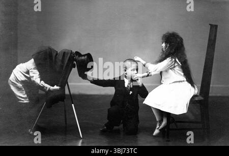 Kinder fotografieren Handkuss, 1920, Ein Junge im Anzug und Hut, der mit zwei anderen Kindern spielt, ein Kind hängt kopfüber auf einem Stuhl, historischer p Stockfoto