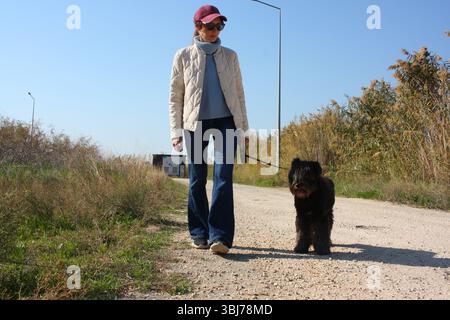 Mädchen, das mit einem schwarzen, süßen Hund läuft, Leine, Hand, Mischling Stockfoto