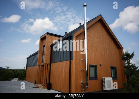 Ein wunderschön gestaltetes Holzhaus mit moderner Architektur und einem hohen Kamin Stockfoto