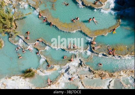 Luftaufnahme der heißen Quellen Saturnia in der Toskana, Italien, mit klarem blauem Wasser, einer rustikalen Wassermühle und Badegästen an einem warmen Sommertag. Stockfoto