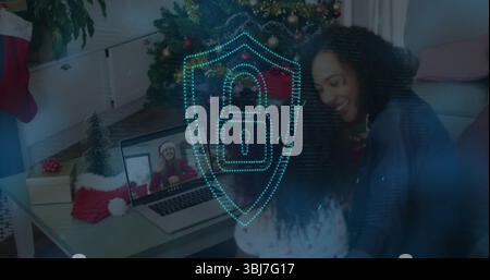 Mutter und Kind teilen ihren Laptop im Wohnzimmer, mit Weihnachtsbaum und digitalem Schild Stockfoto