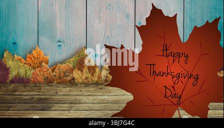 Mit rotem Ahornblatt mit Happy Thanksgiving Day auf dem Tisch mit türkisfarbenen Tafeln, getrockneten Blättern Stockfoto