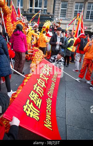 Die Menge versammelt sich zu einem chinesischen Neujahrsfest mit lebhaften Kostümen und dem roten newcastle chinese Schulbanner newcastle upon tyne Stockfoto