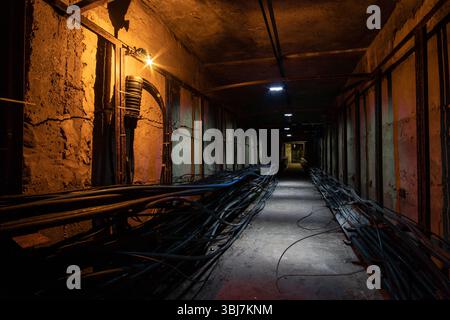 Unterirdischer Kabeltunnel mit einer Kabelkupplung im Vordergrund. Unterirdischer Tunnel mit optischen Kabeln für Internet, Fernsehen und Telefon. Stockfoto